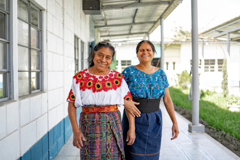 Two women standing next to each other in front of a building