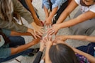 A group of people standing in a circle with their hands together