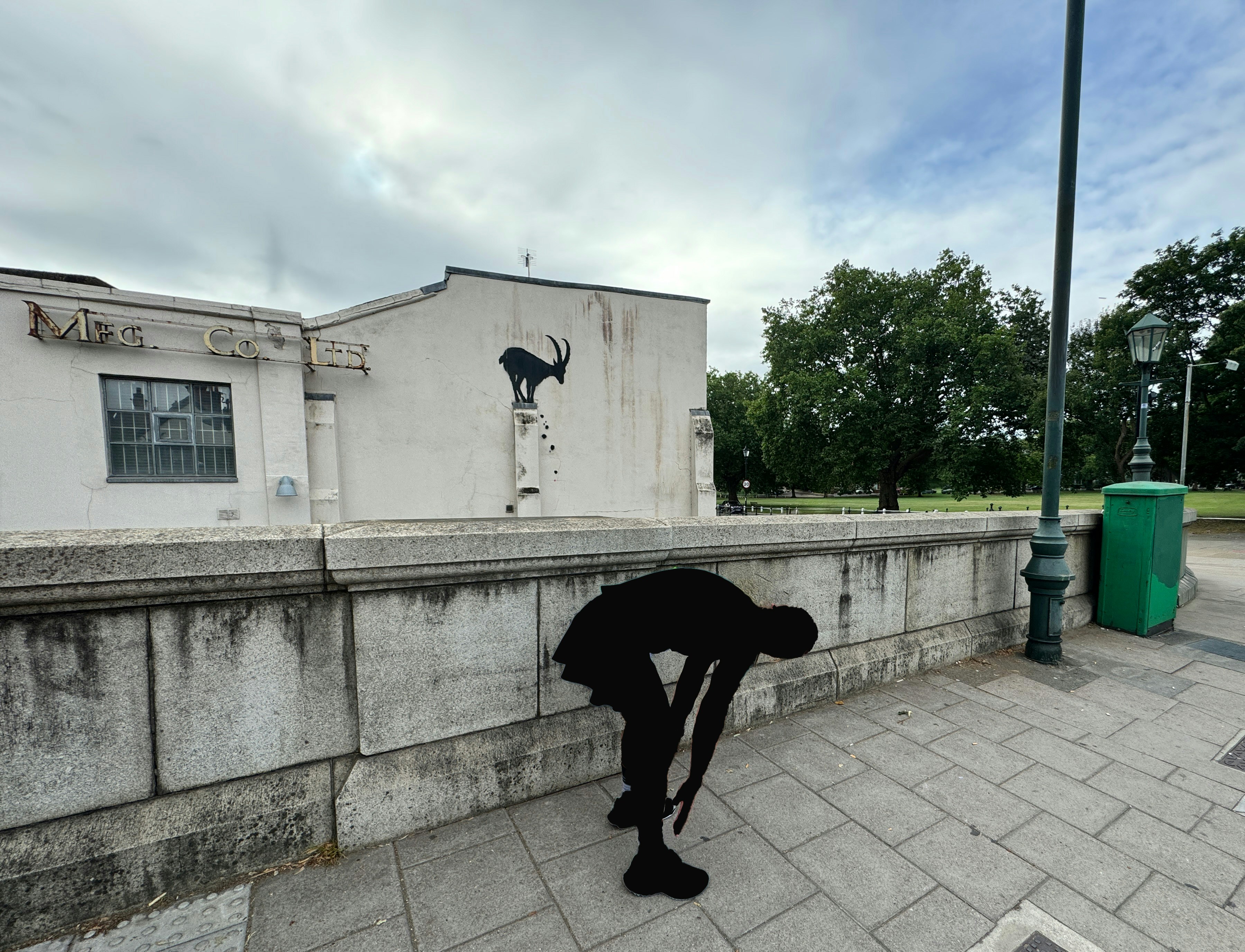 A person with a black umbrella on a sidewalk