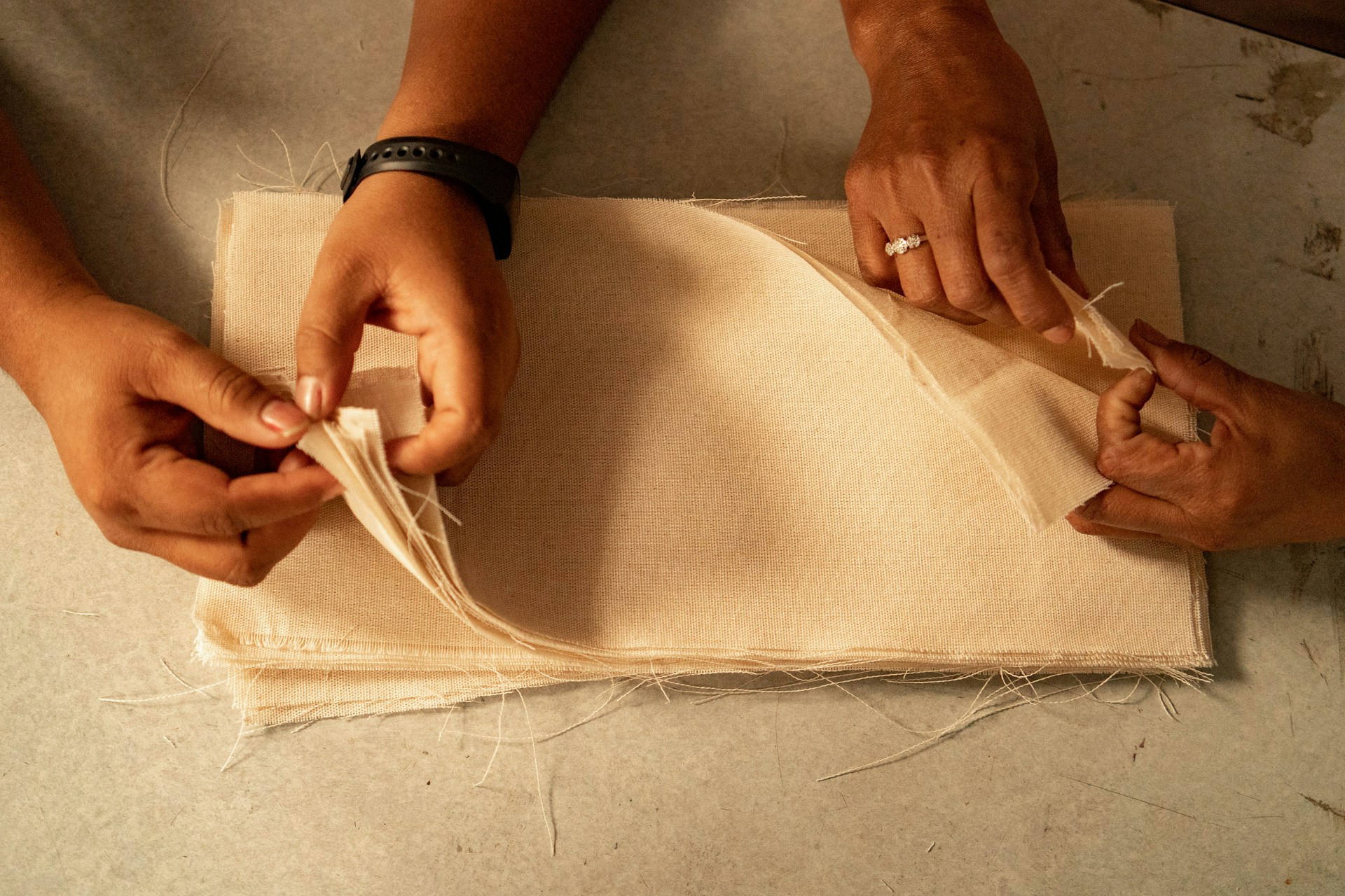 Two people are working on a piece of cloth