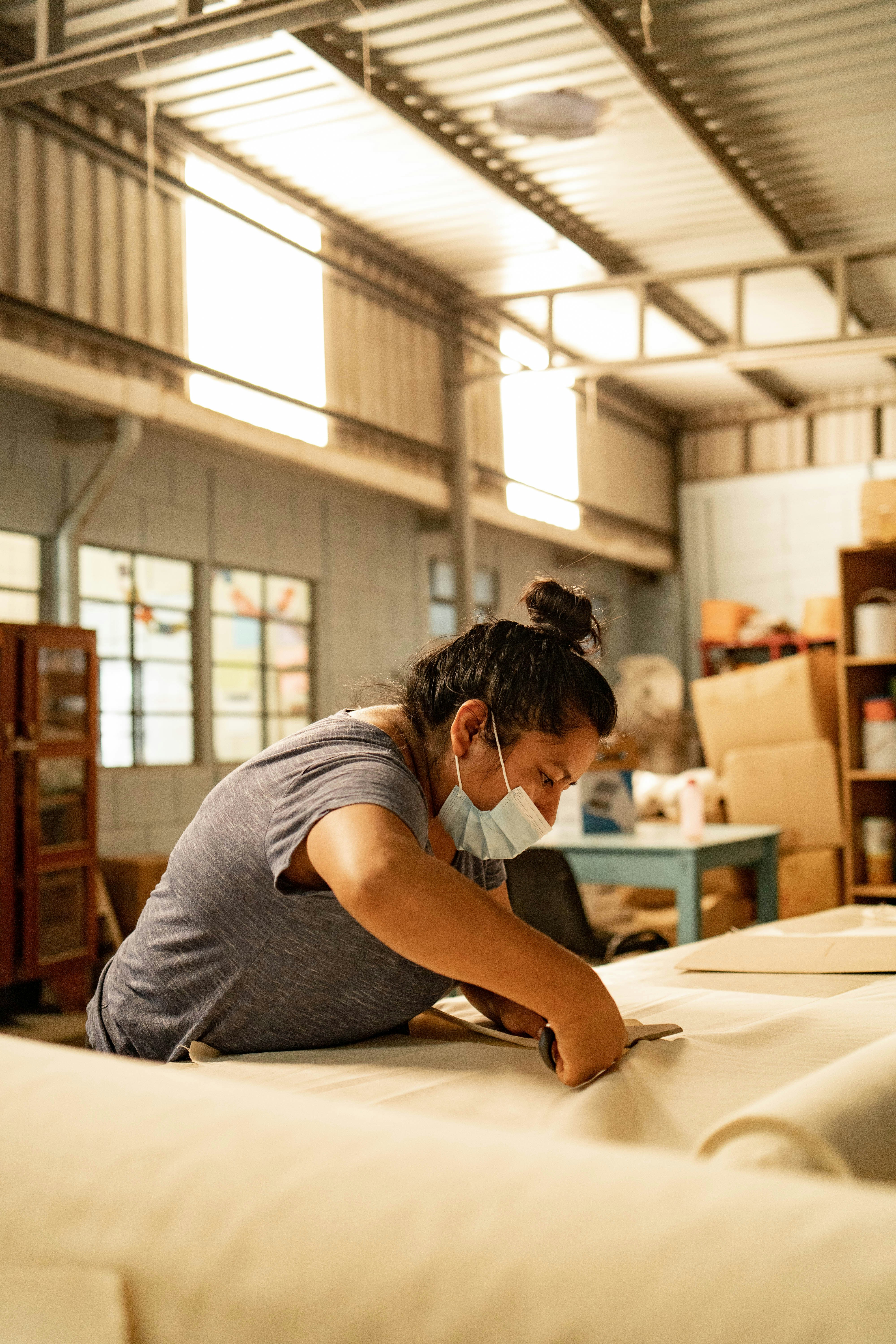 A woman in a mask is working on a mattress