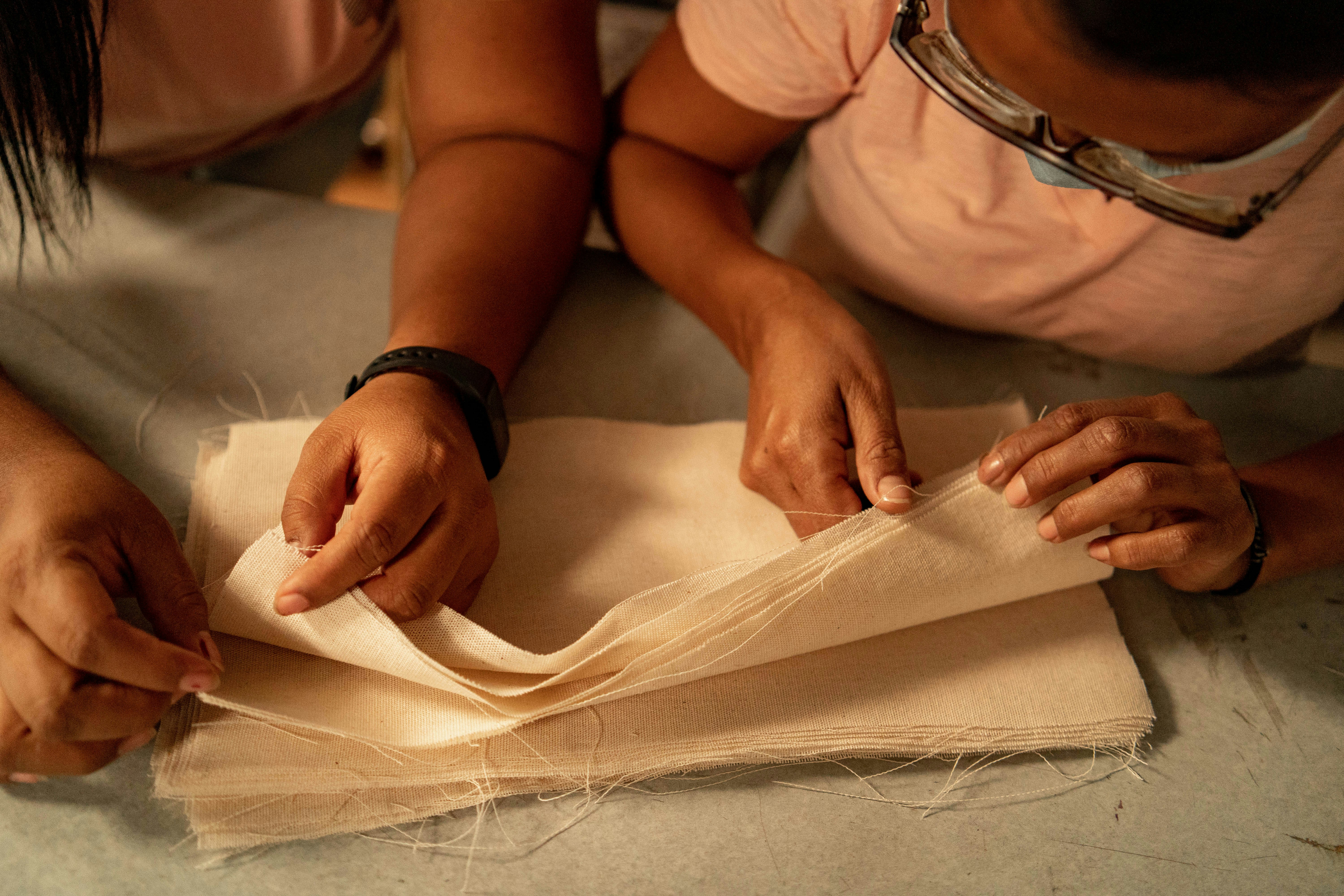 Two women are working on a piece of cloth