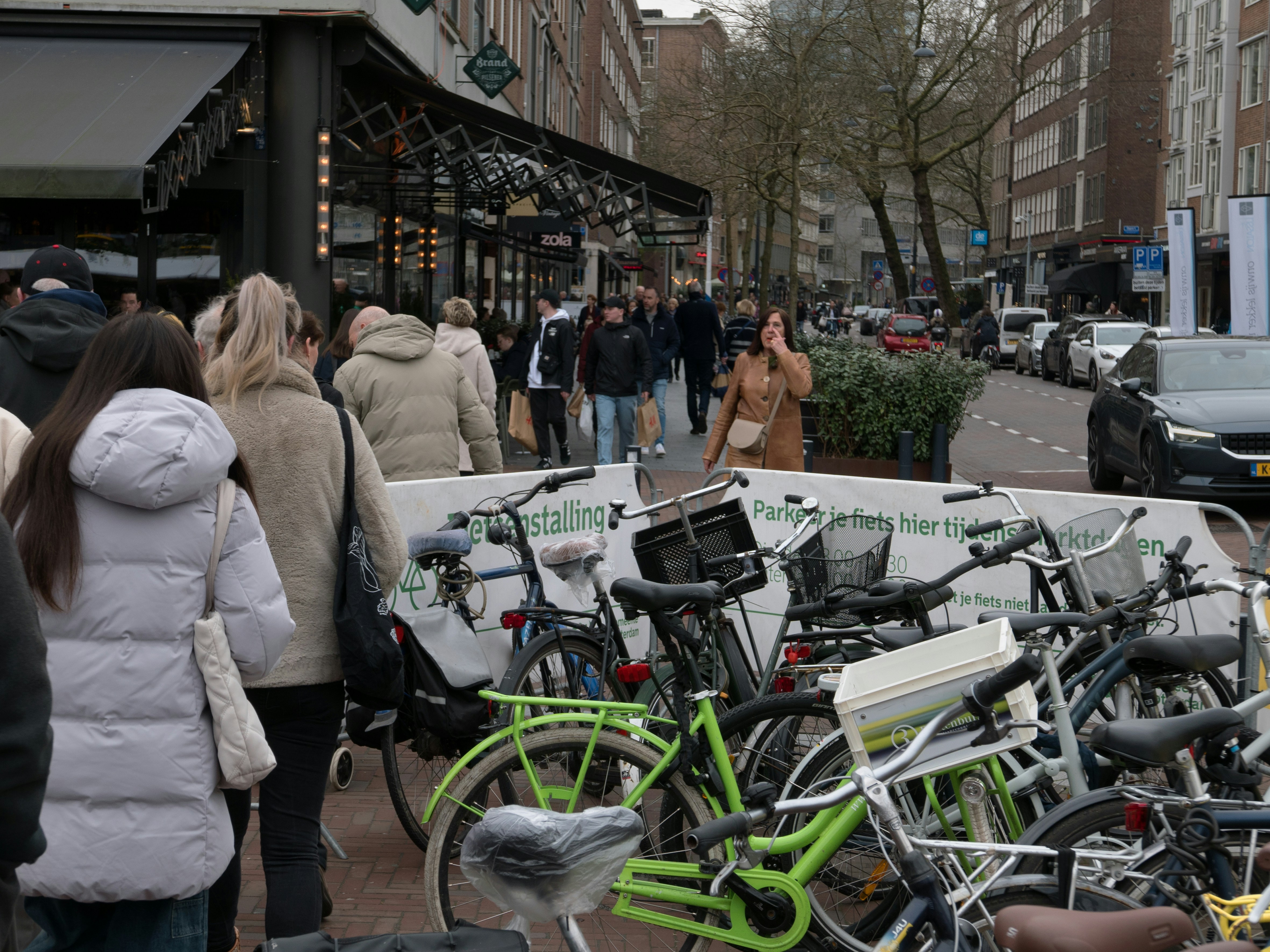 Local Dutch people are shopping at the shopping street - close to the market on Saterday, on a grey winter day; location is close tot the street Binnenrotte in Rotterdam city. This is a place for parking your bike on market days. Street photography of The Netherlands - free download image of Fons Heijnsbroek, Dutch photographer.