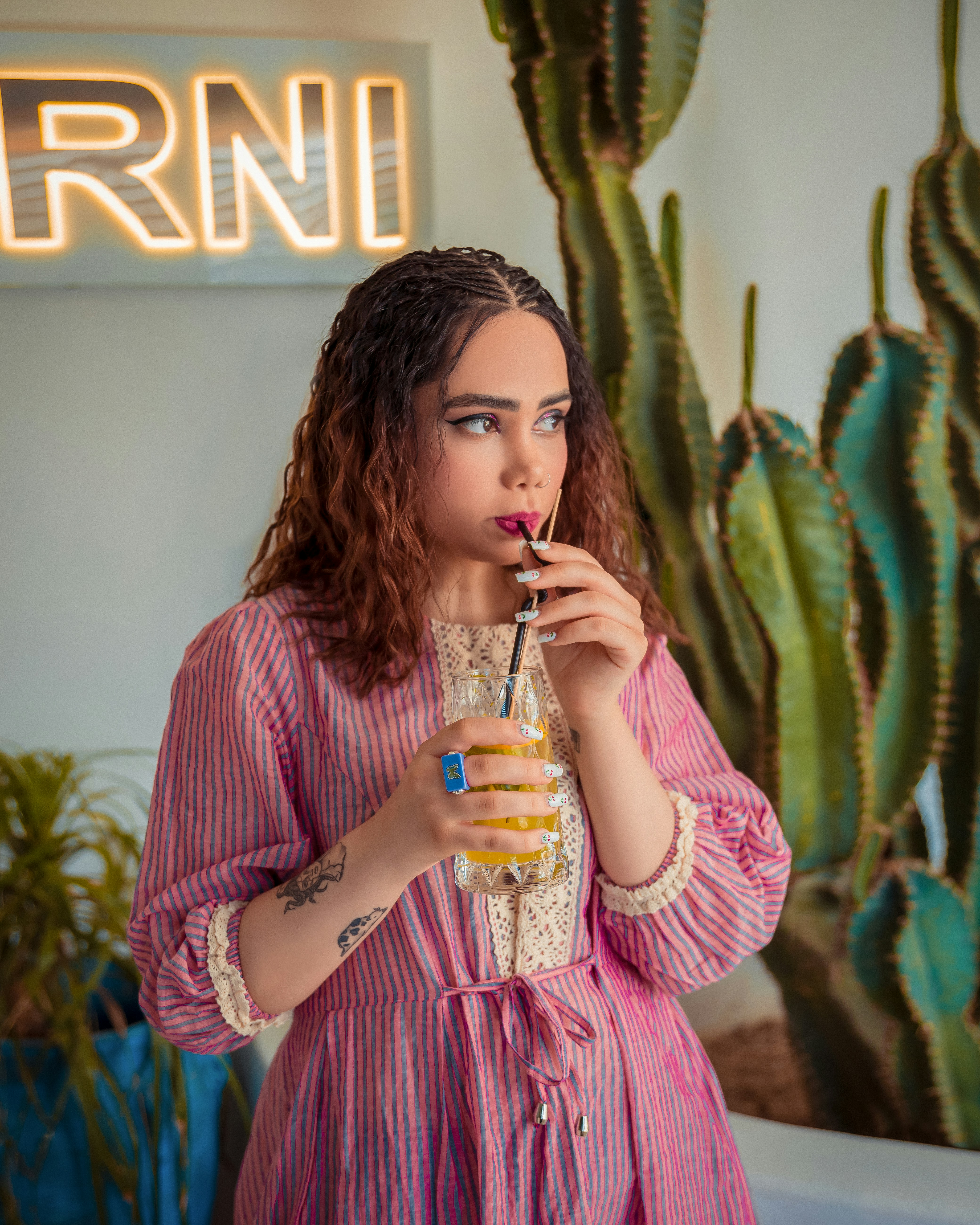 Una donna in un vestito rosa che beve un drink