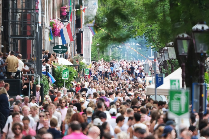A crowd of people walking down a street next to tall buildings