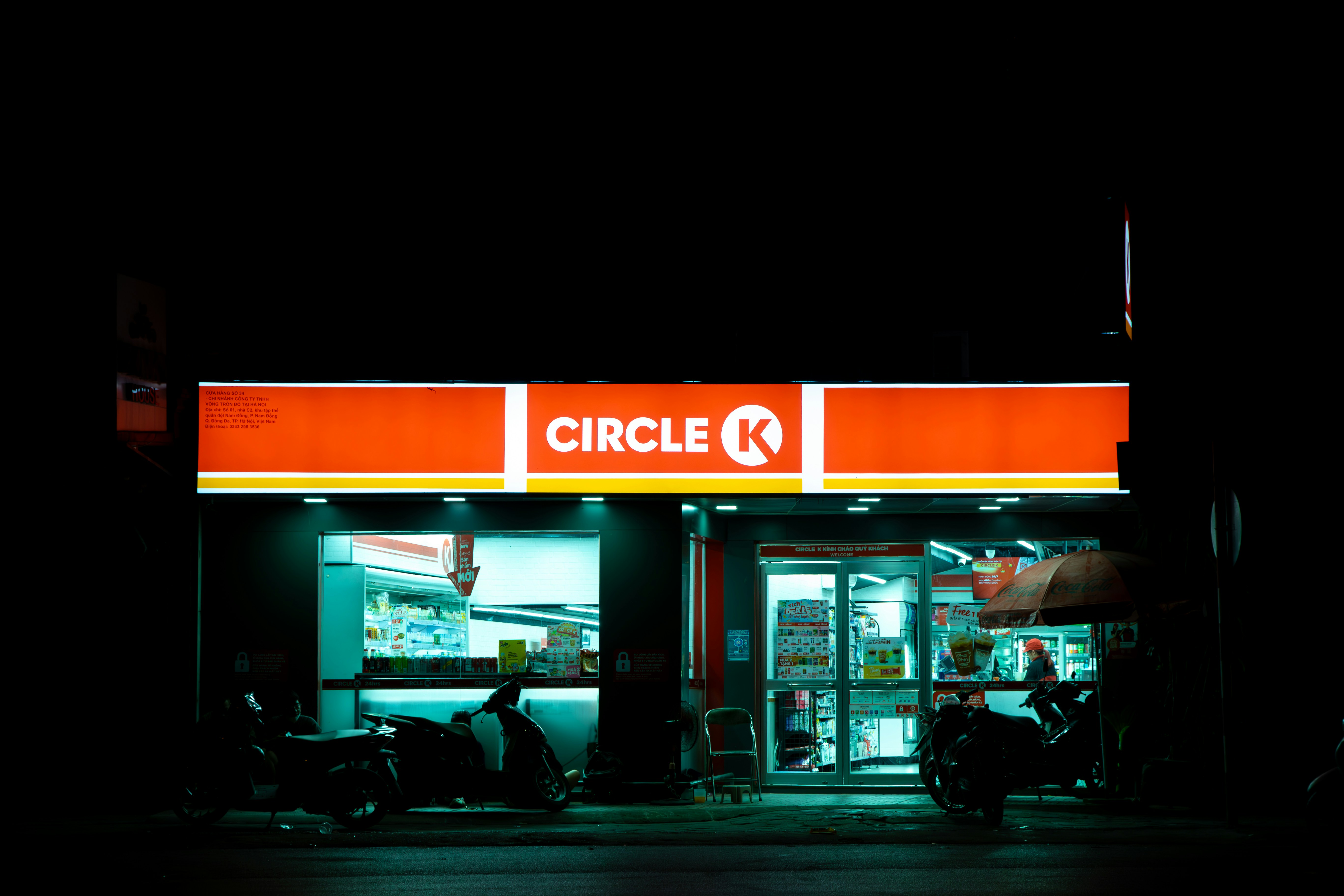 A store front at night with a motorcycle parked in front of it