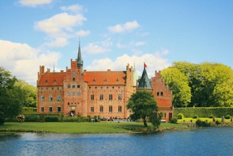 A large building sitting on top of a lush green field next to a lake
