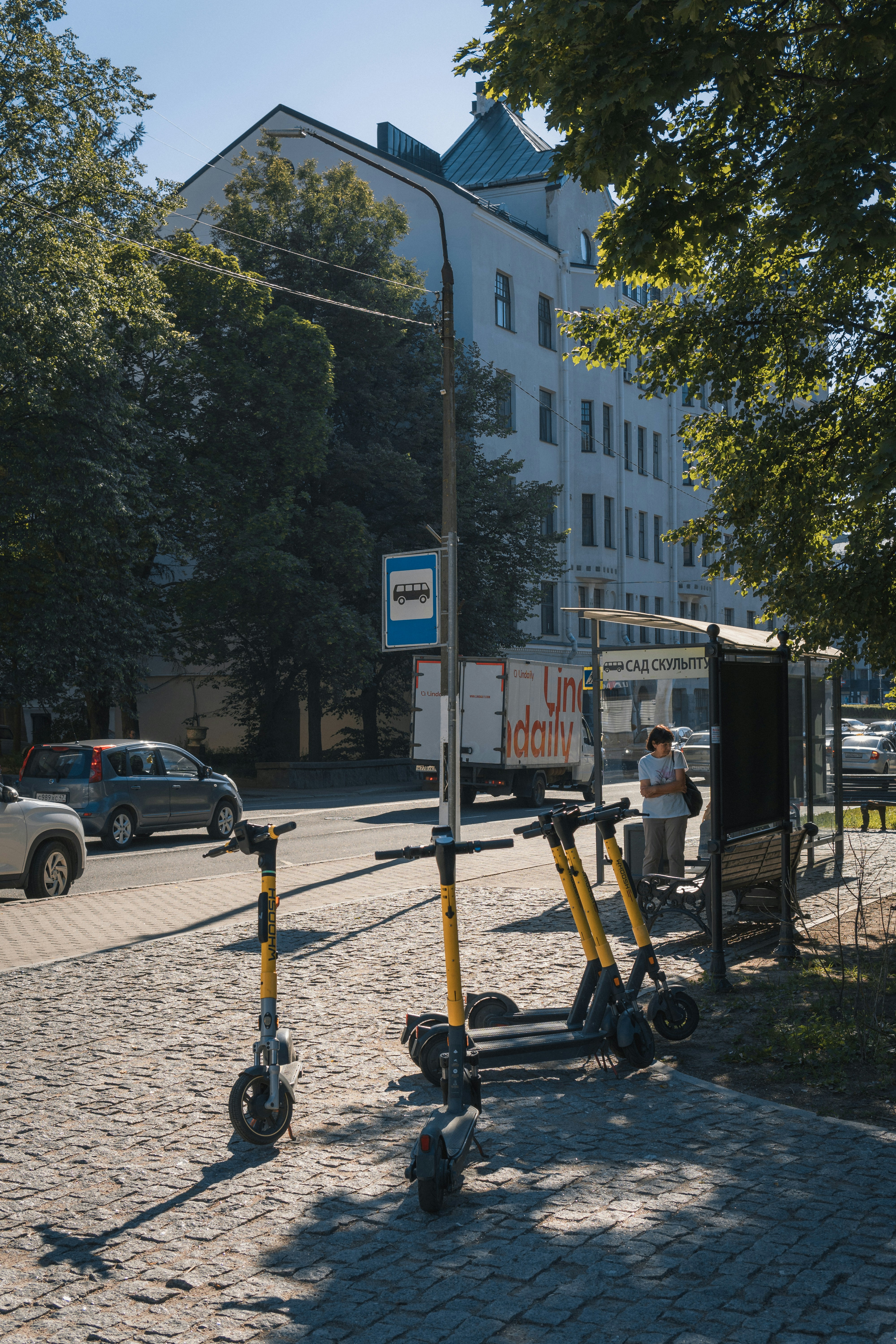 A man is standing on a scooter in the street