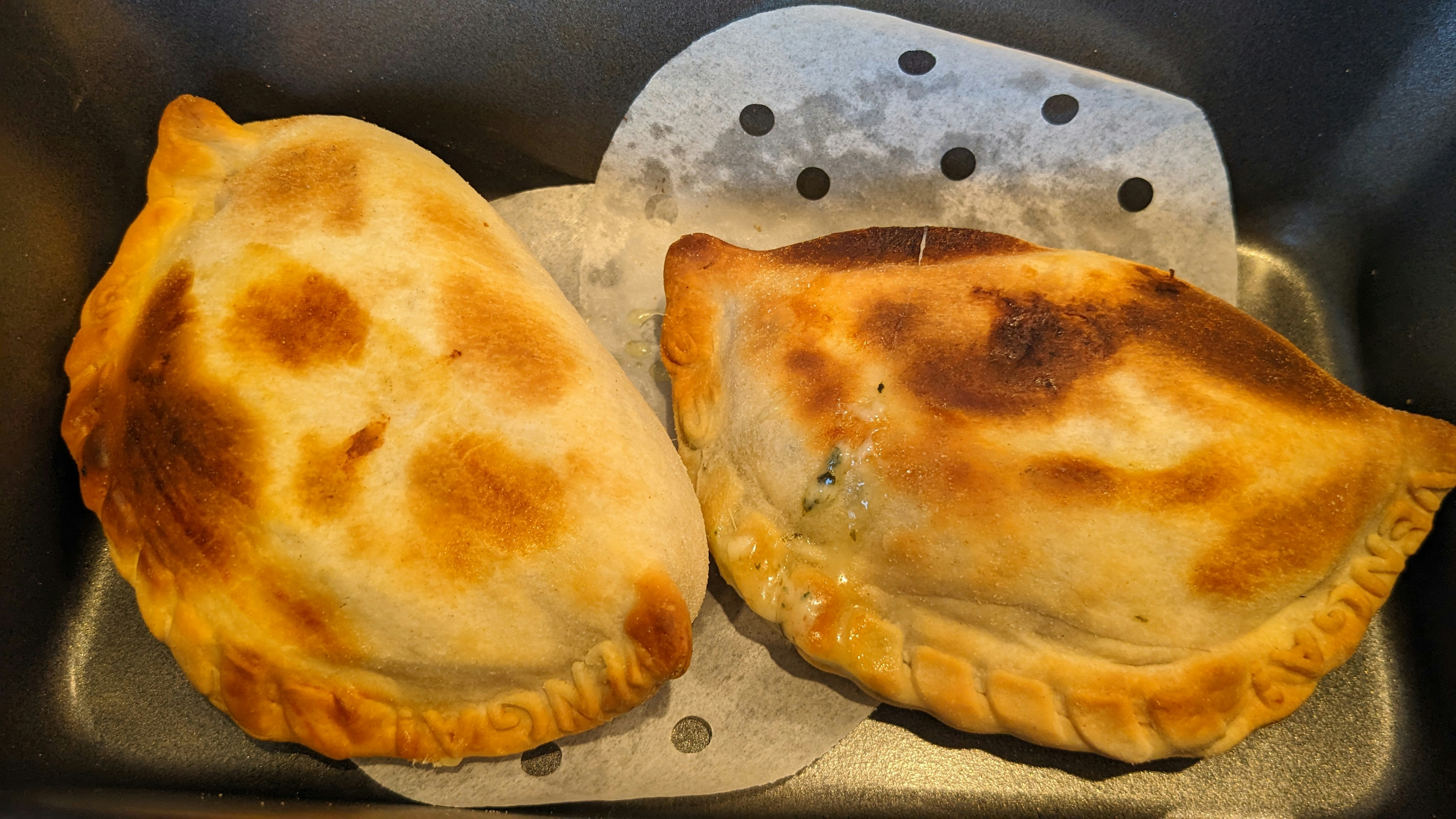 Empanada de carne con relleno jugoso visible, fondo oscuro cálido