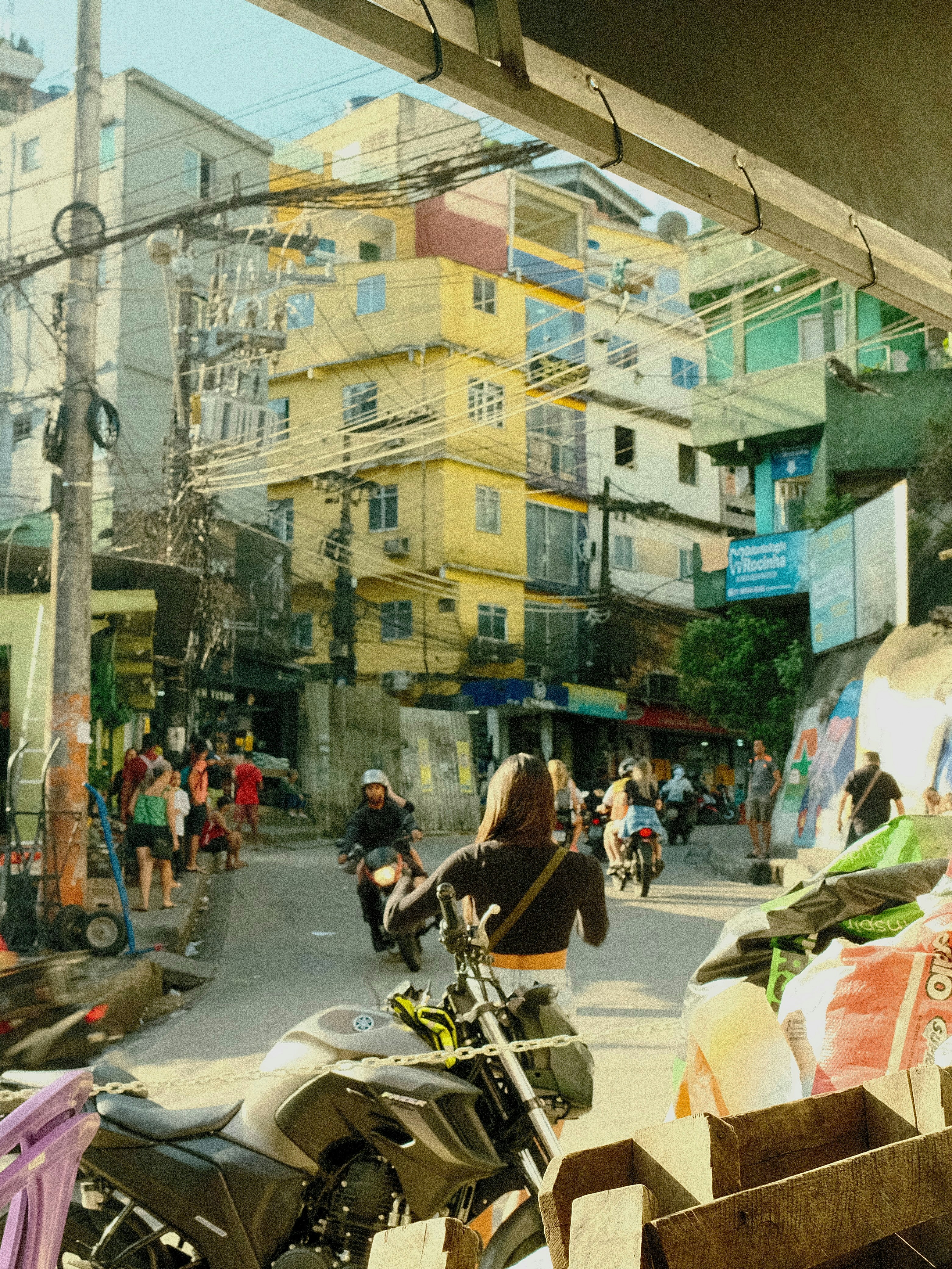 A group of people walking down a street next to parked motorcycles