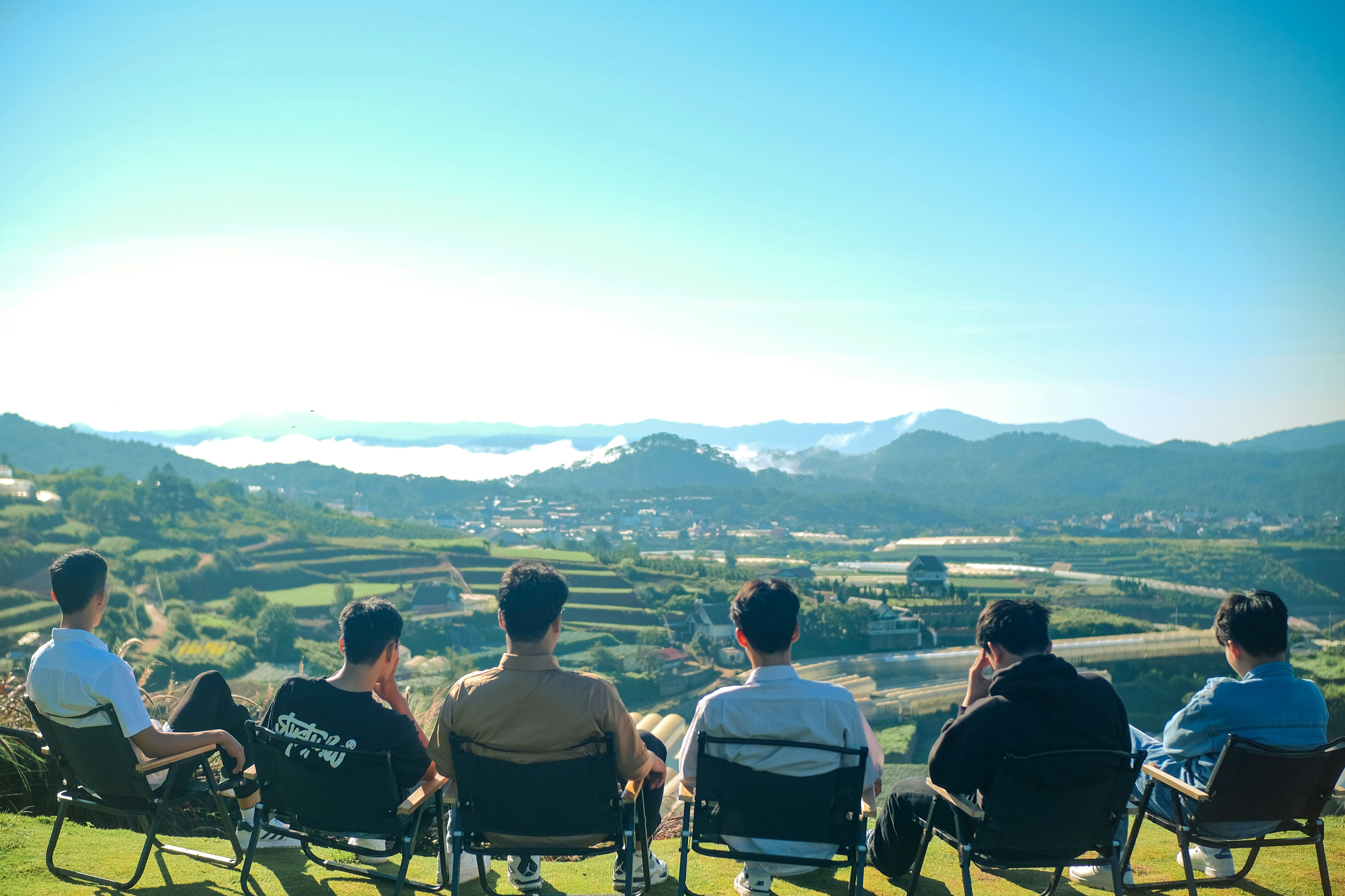 A group of people sitting on top of a lush green hillside