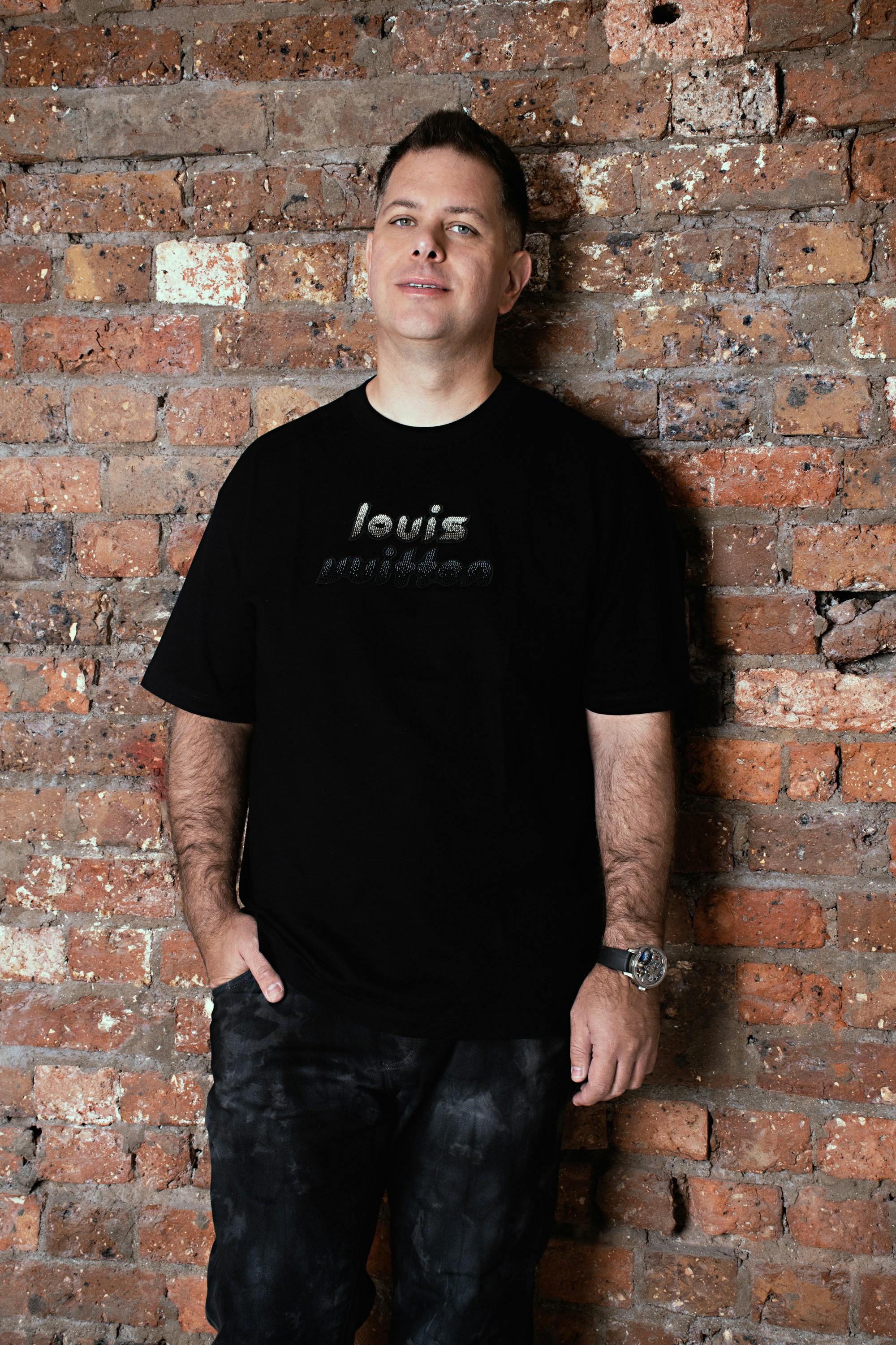 A man standing in front of a brick wall