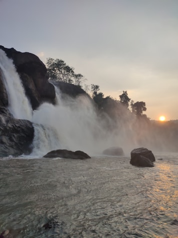 The sun is setting behind a waterfall