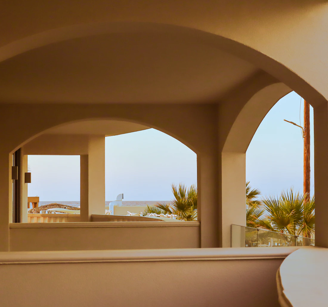 Arched terrace opening onto palms and sky