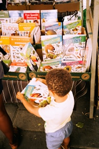 A boy and a woman standing in front of a book stand