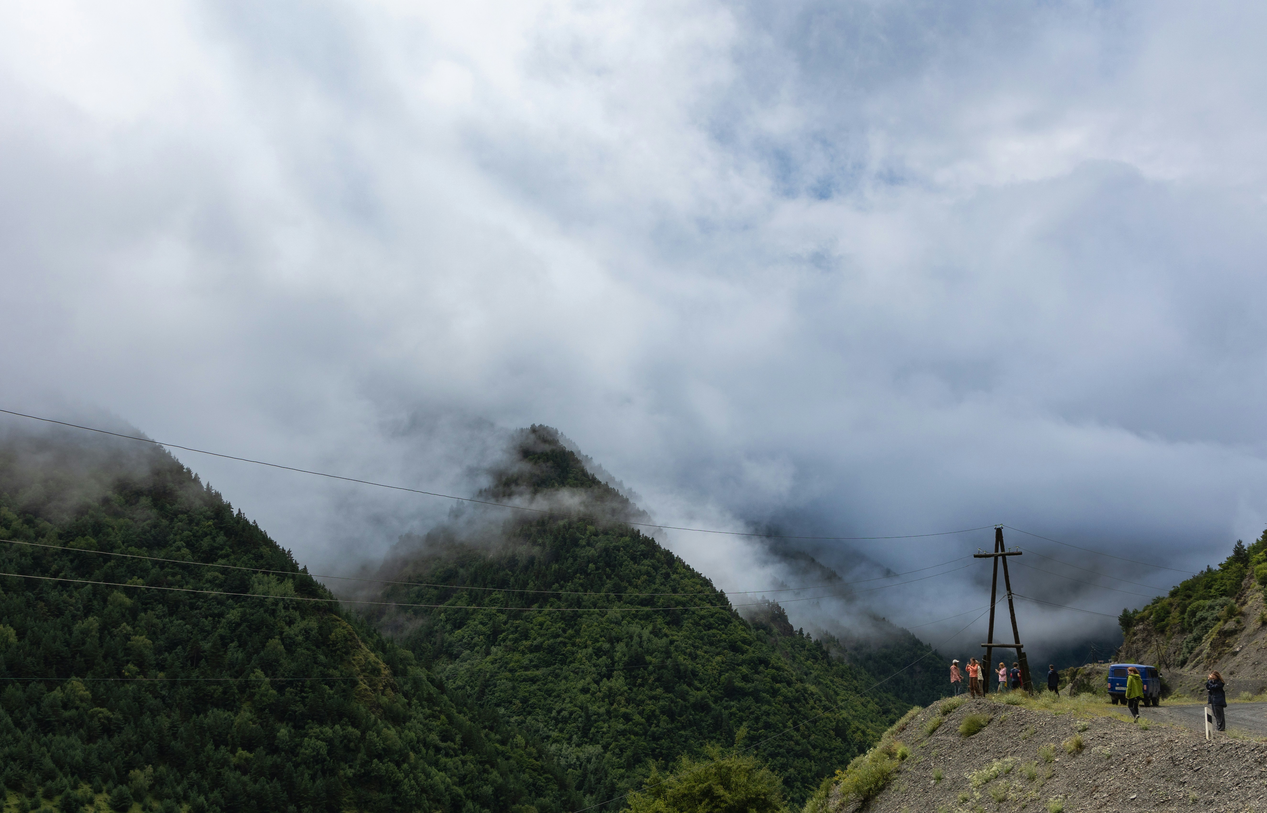 A group of people standing on top of a lush green hillside