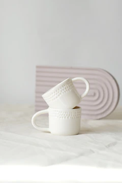 A stack of white cups sitting on top of a bed