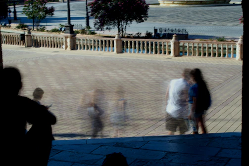 A group of people walking down a sidewalk next to a river