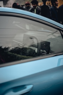 A blue car parked in front of a crowd of people