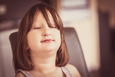 A little girl sitting in a chair with her eyes closed