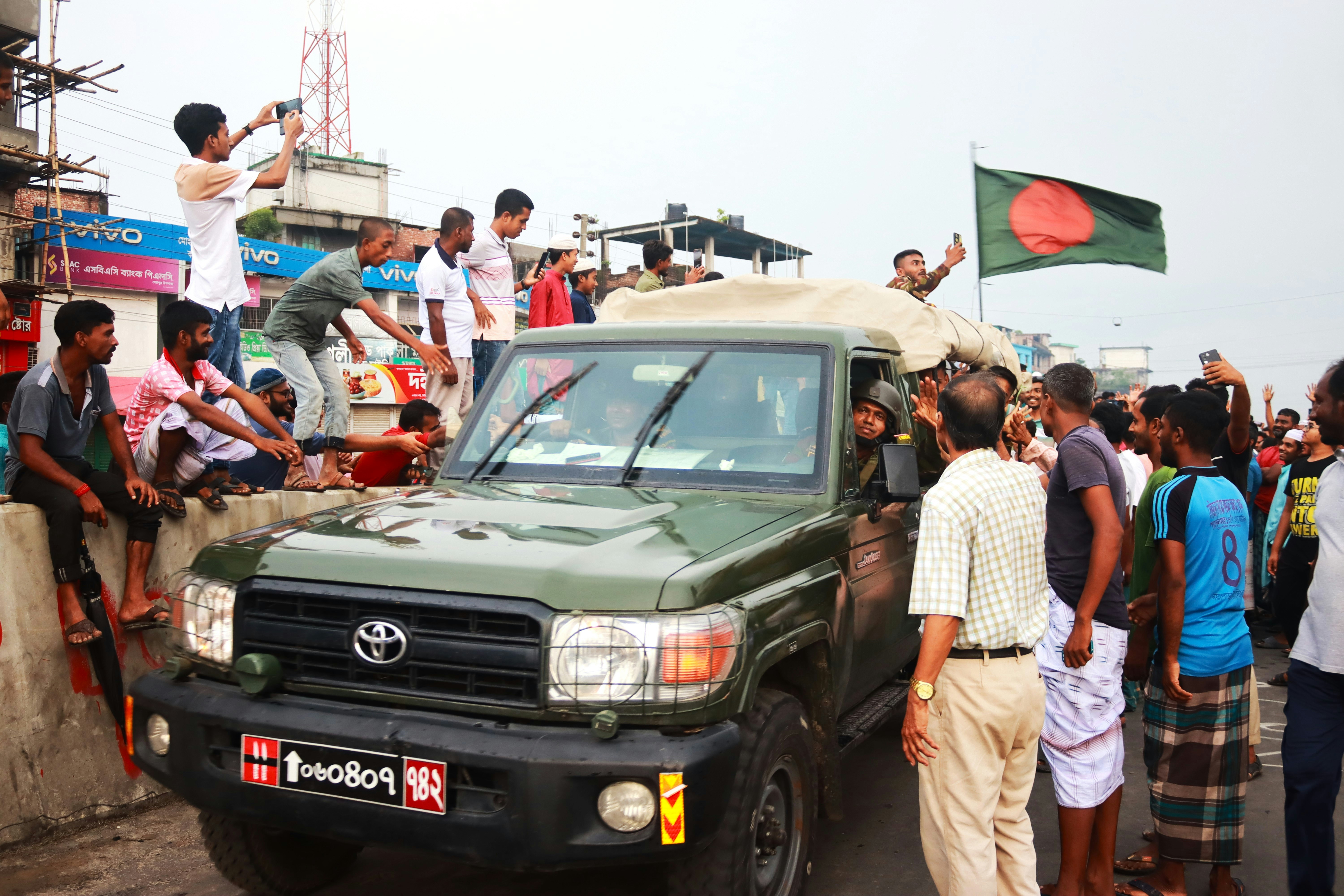 A group of people standing around a green truck