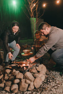 A man and a woman cooking food over a fire