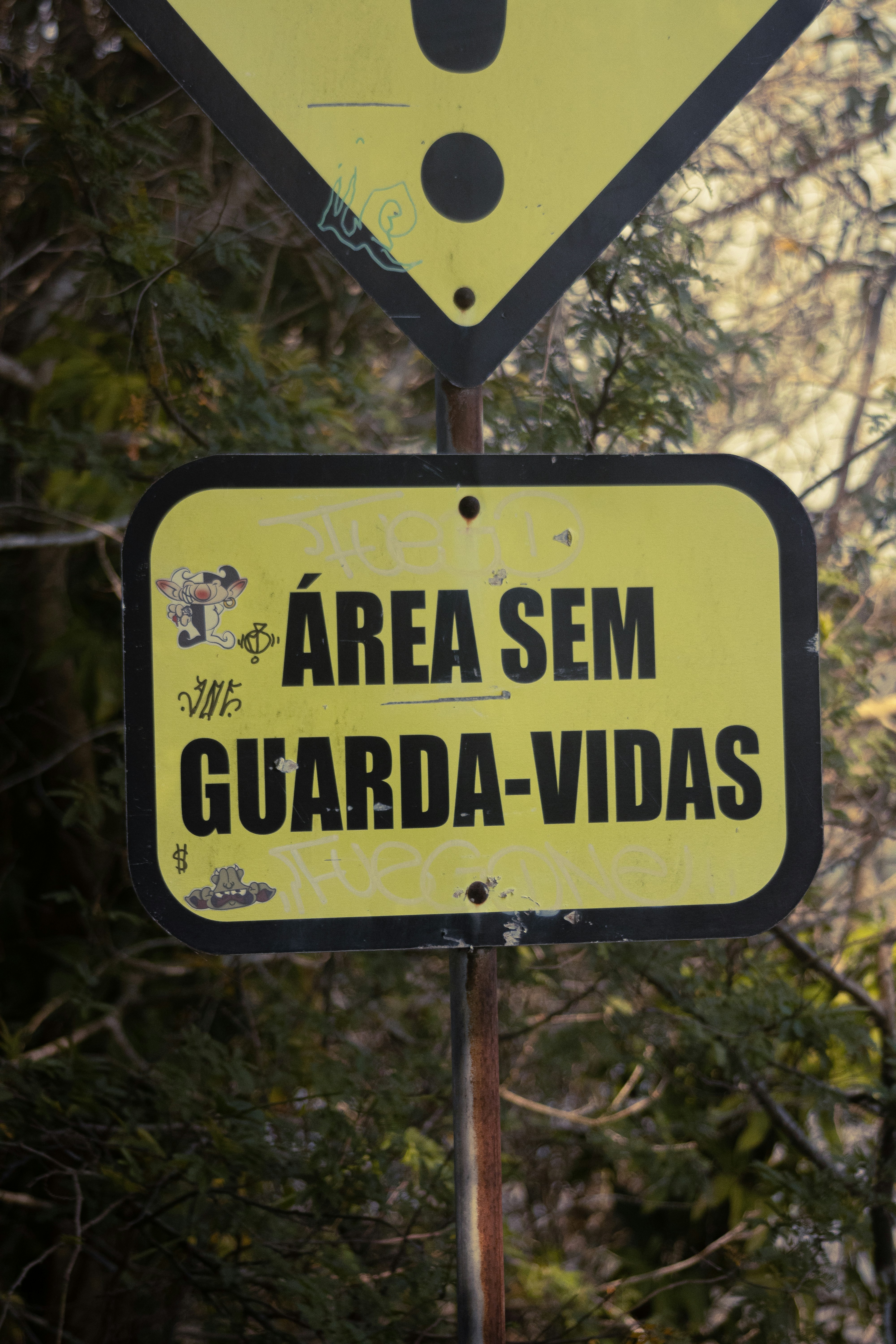 A yellow and black sign that says area sem guarda - vidas