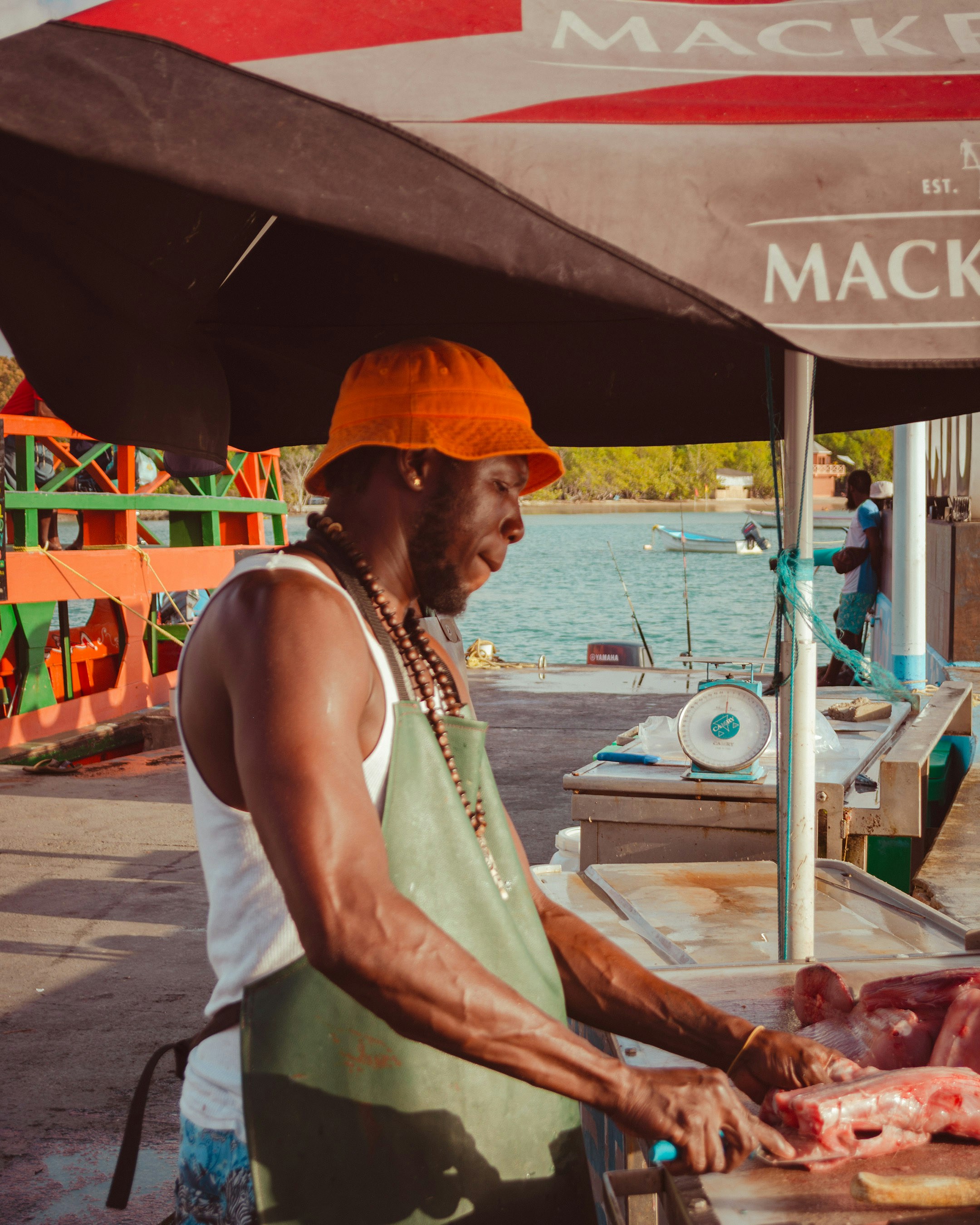 A man in an orange hat is cutting meat