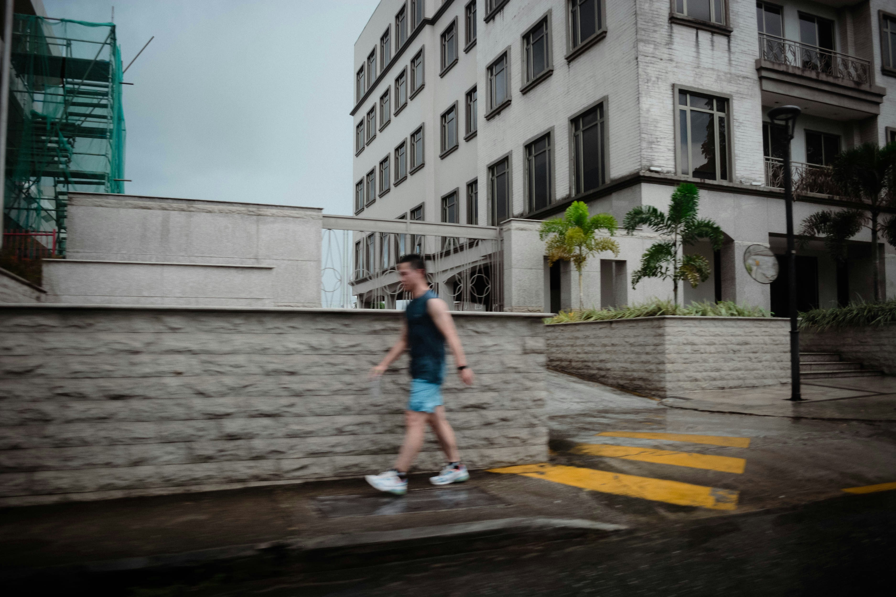 A man walking across a street next to a tall building