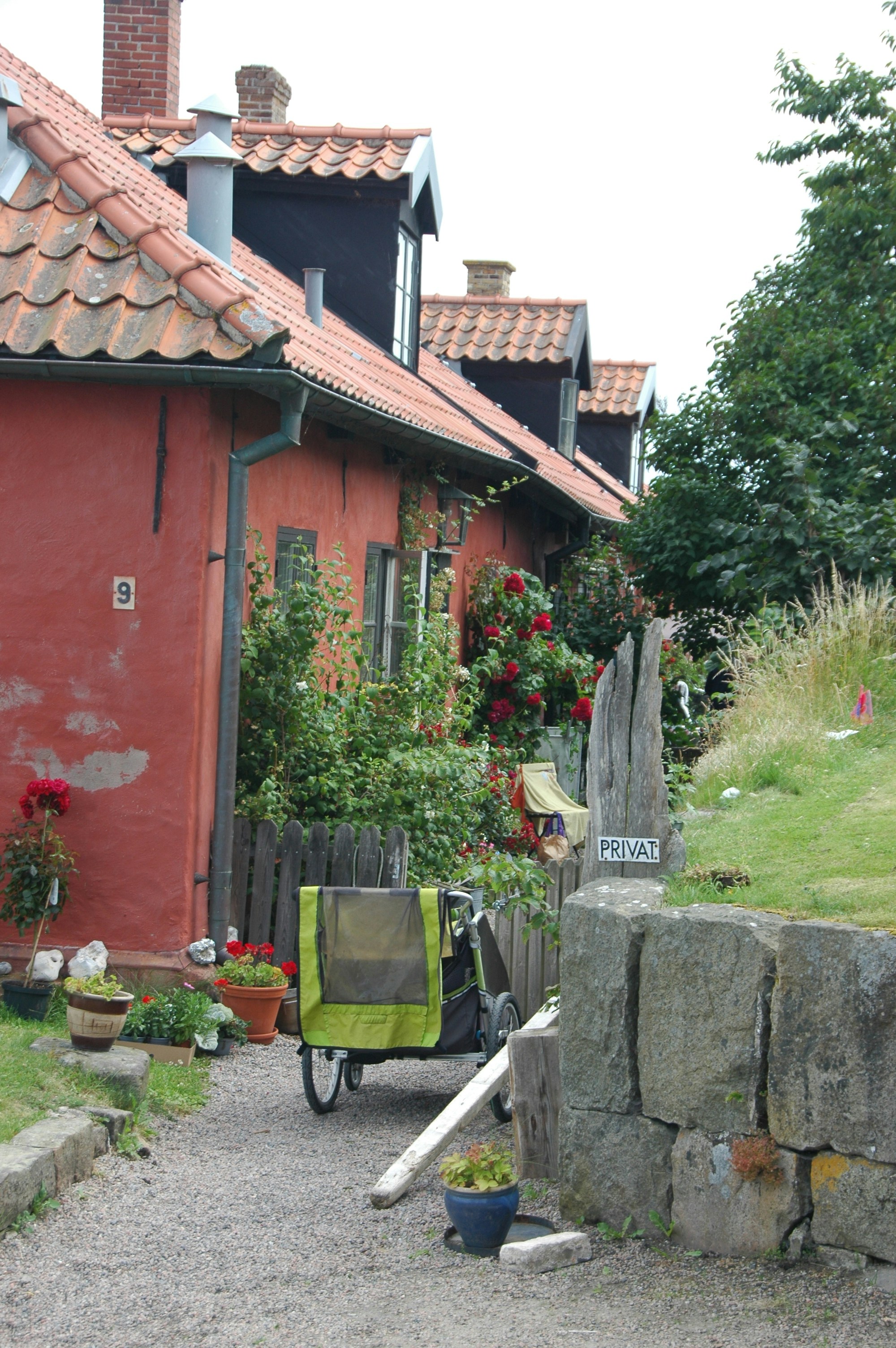 A red building with a red roof next to a stone wall