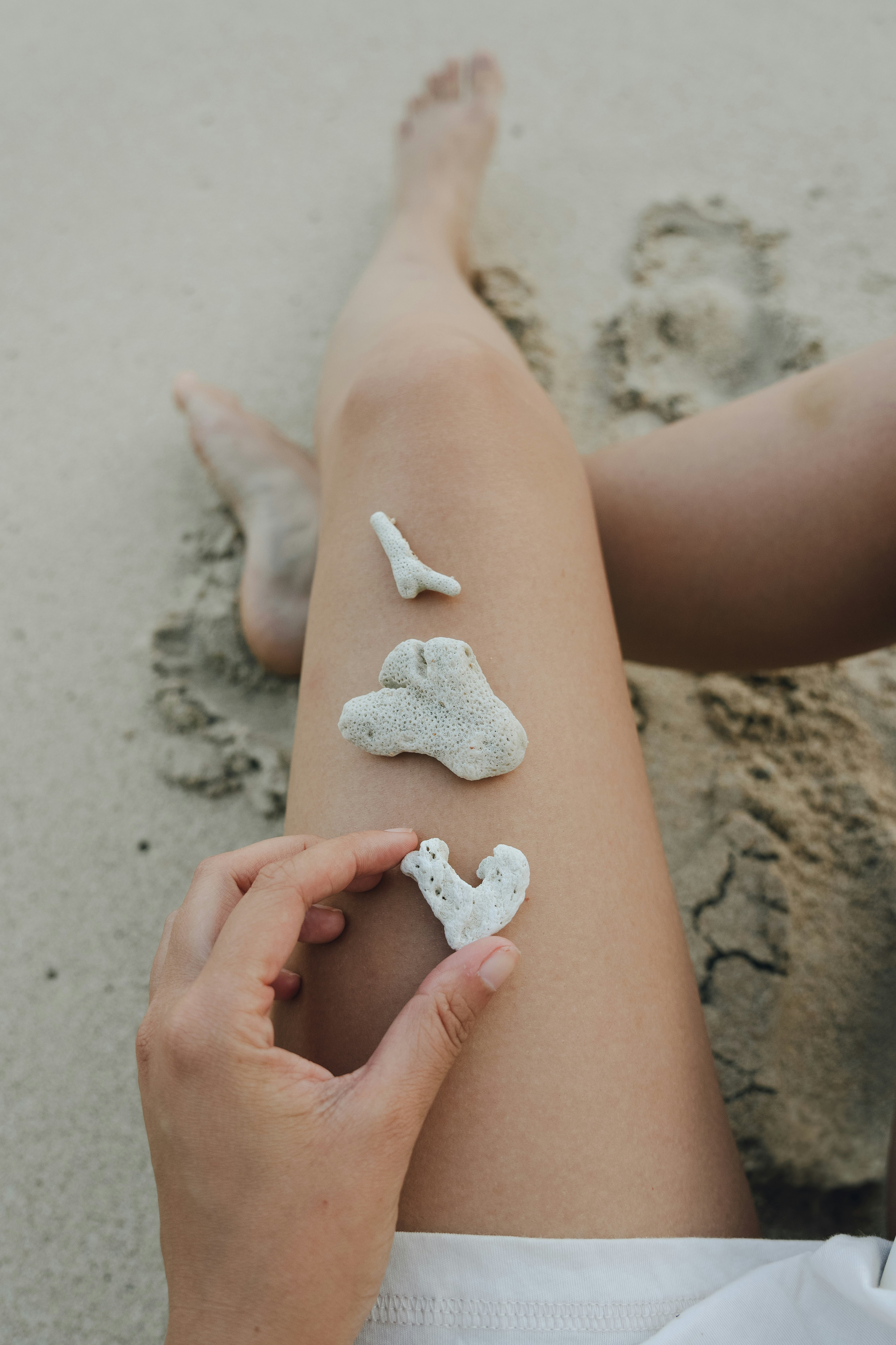 A person sitting in the sand with white sand on their legs