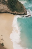 An aerial view of a sandy beach with a cliff in the background