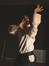 A man standing in a room holding his arms up in the air