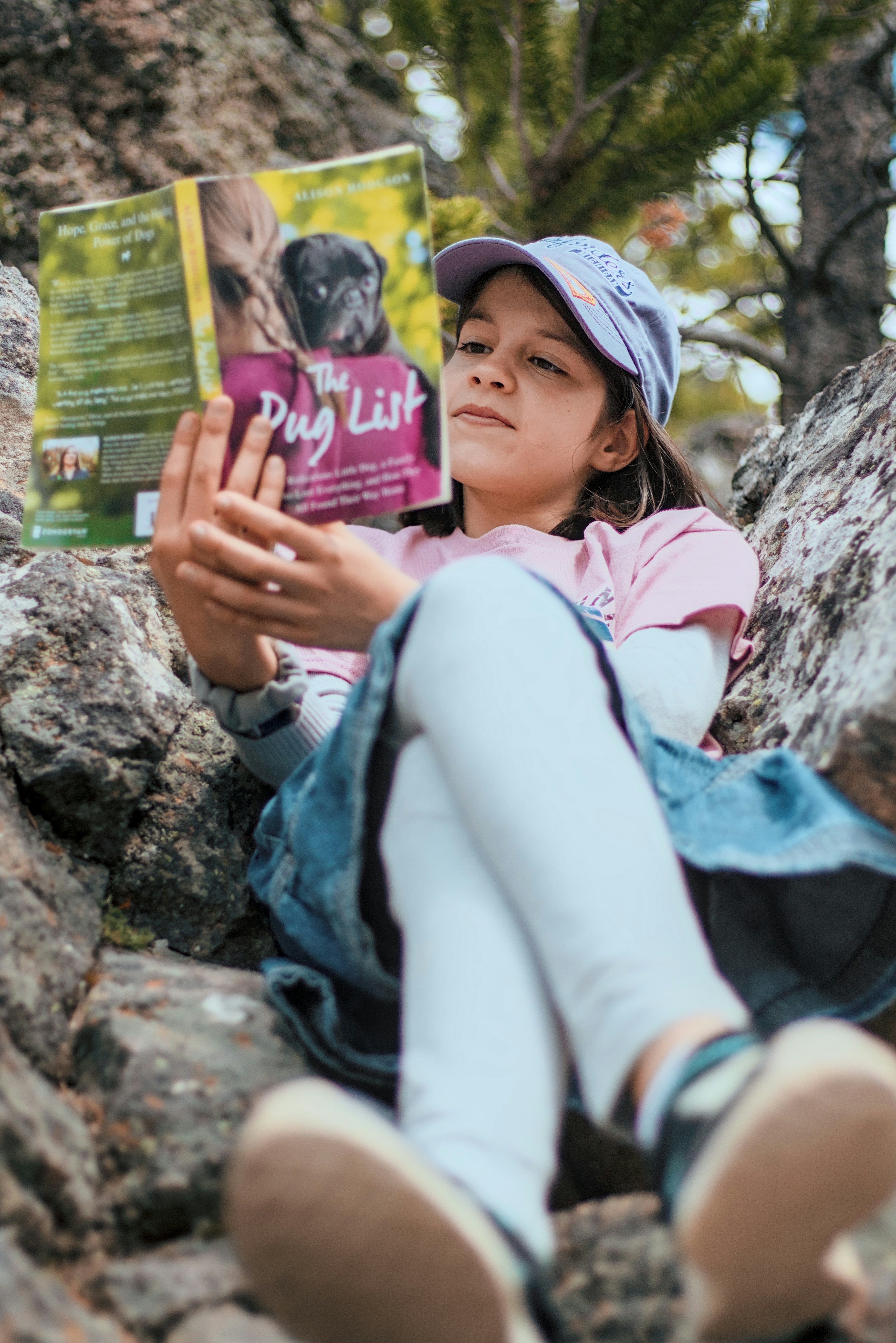 Une jeune fille assise sur un rocher lisant un livre