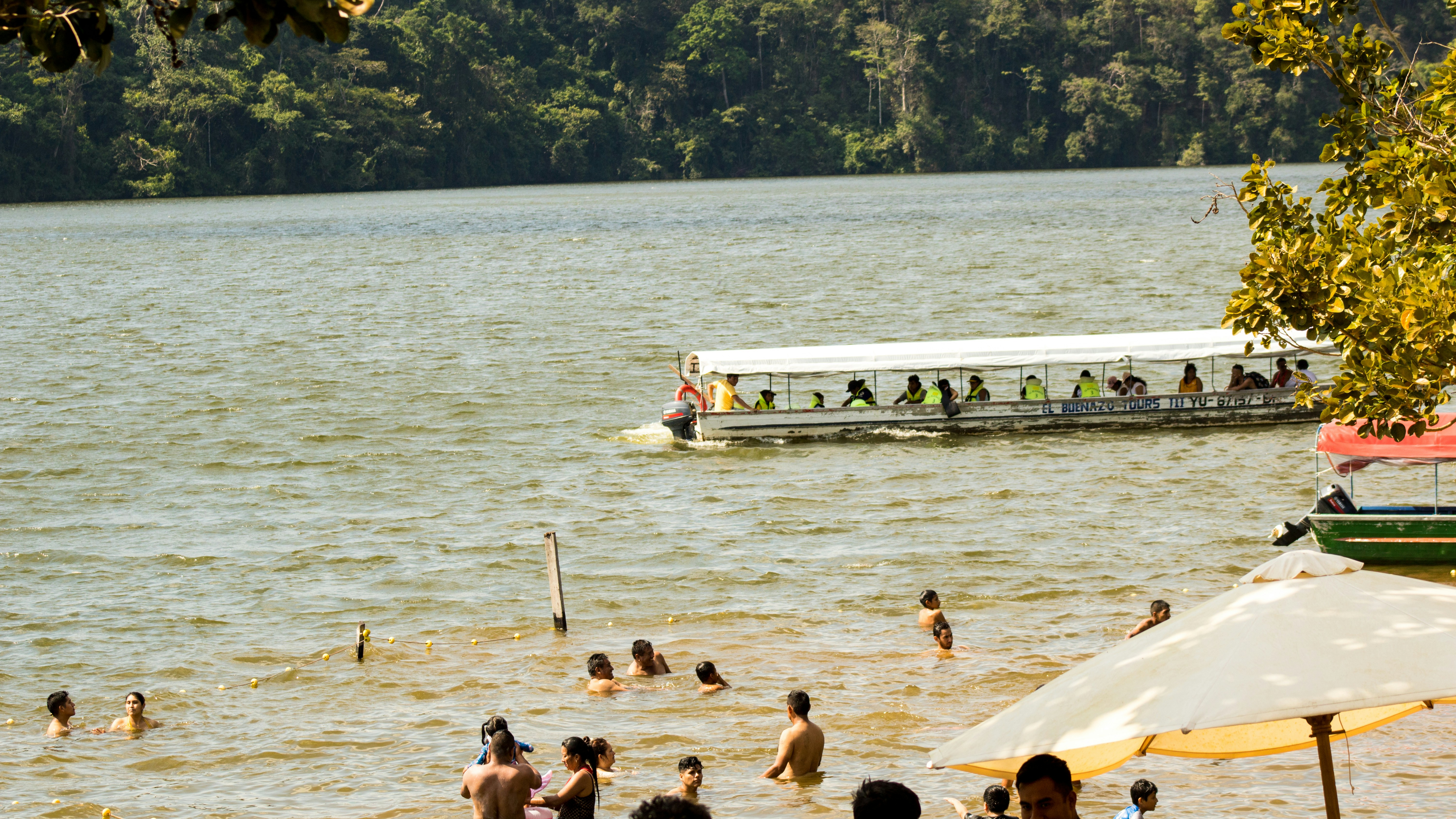 A group of people swimming in a lake next to a boat