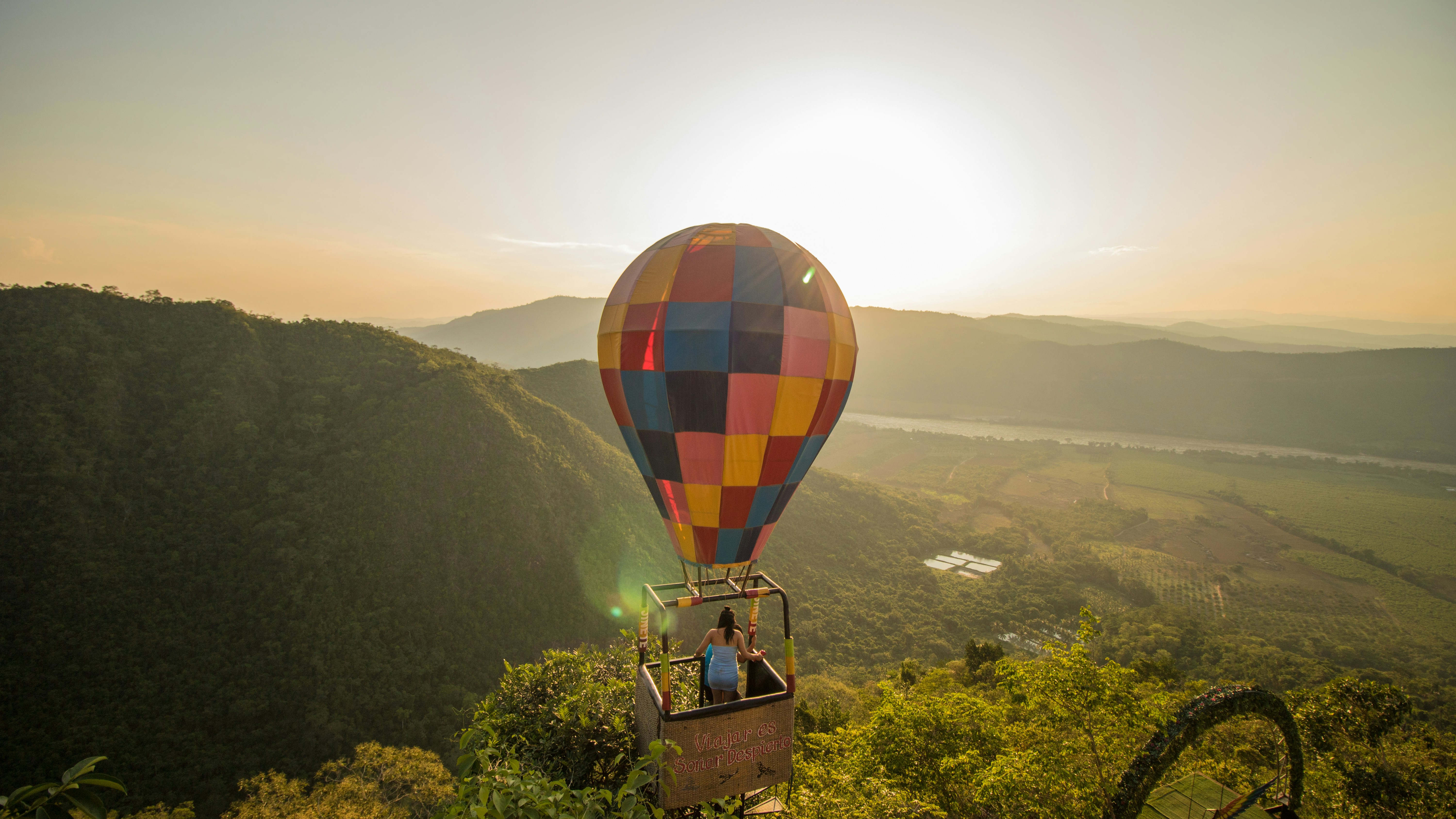 A hot air balloon flying over a lush green hillside
