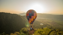 A hot air balloon flying over a lush green hillside