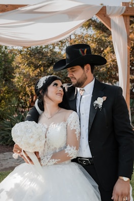 A bride and groom pose for a picture under a wedding arch