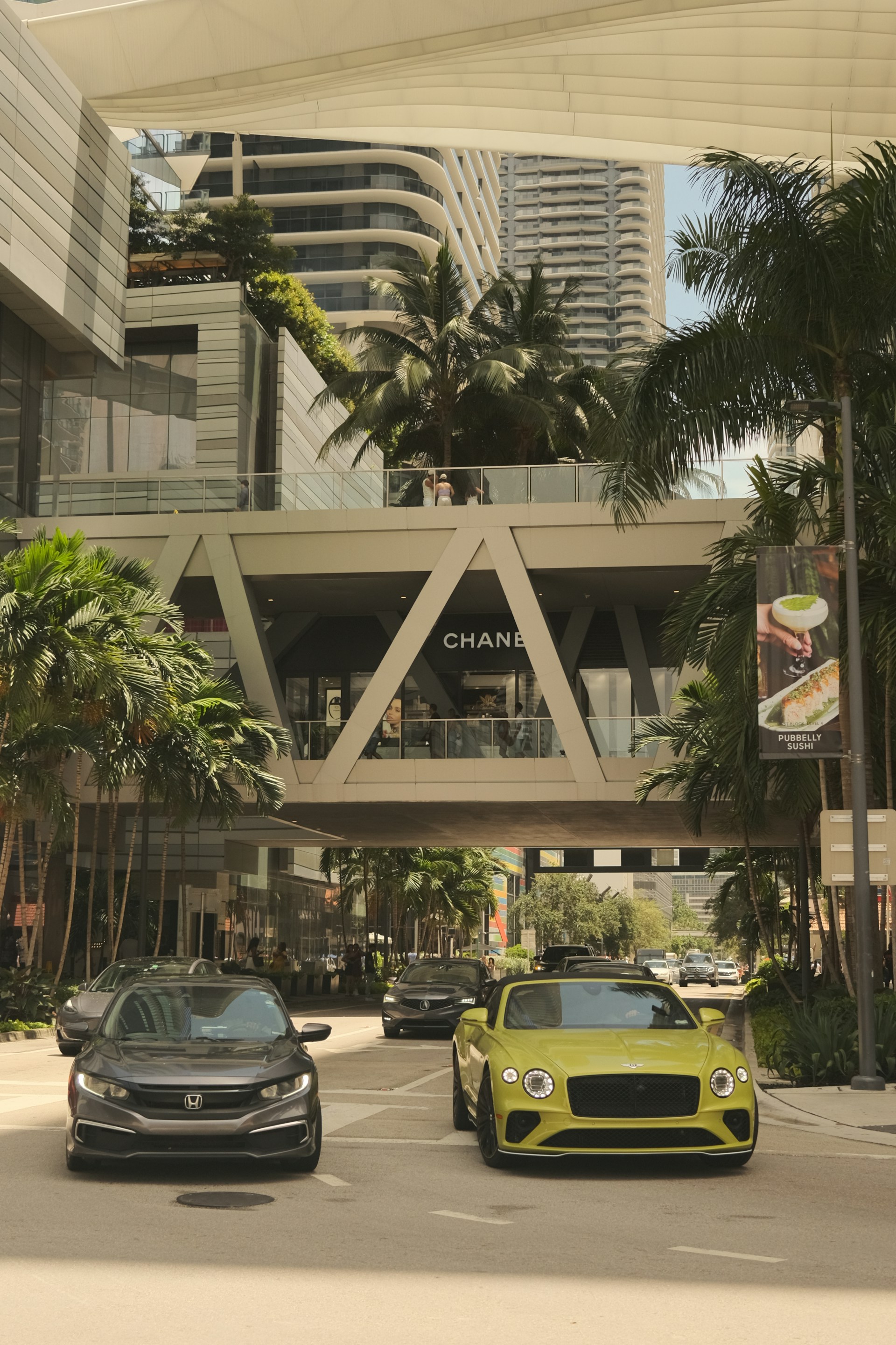 A couple of cars driving down a street next to tall buildings