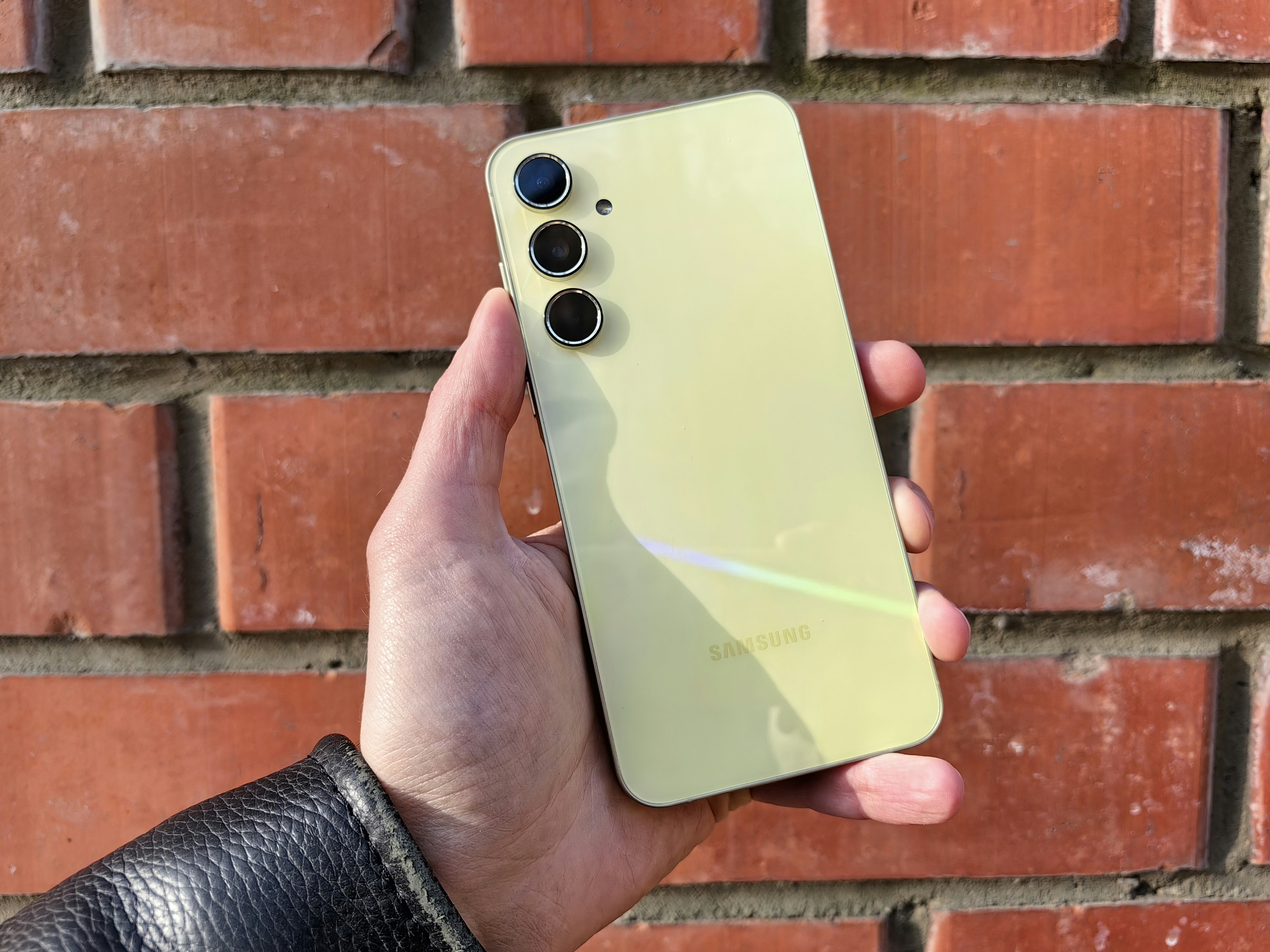 A person holding a cell phone in front of a brick wall