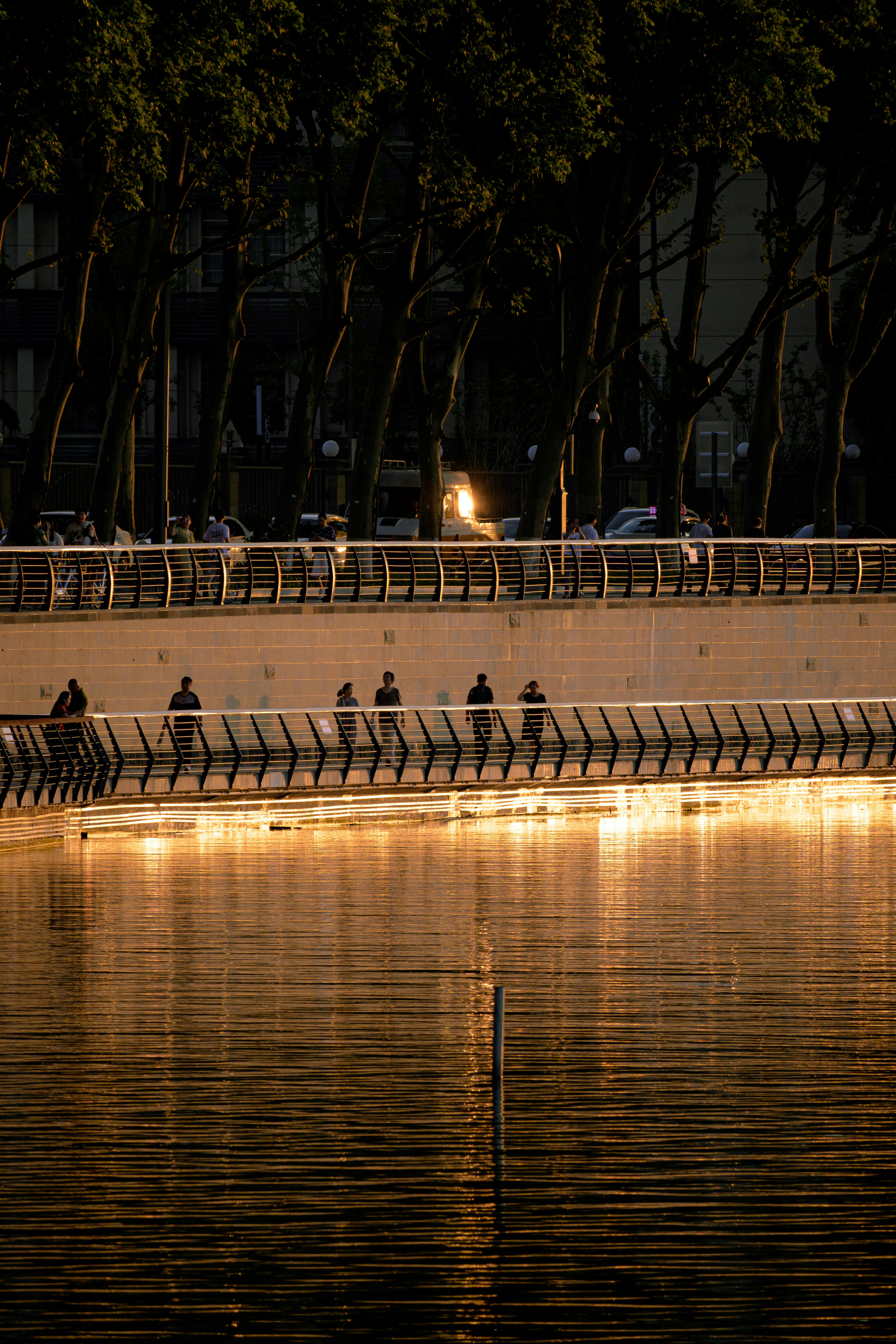 A group of people sitting on benches next to a body of water photo ...