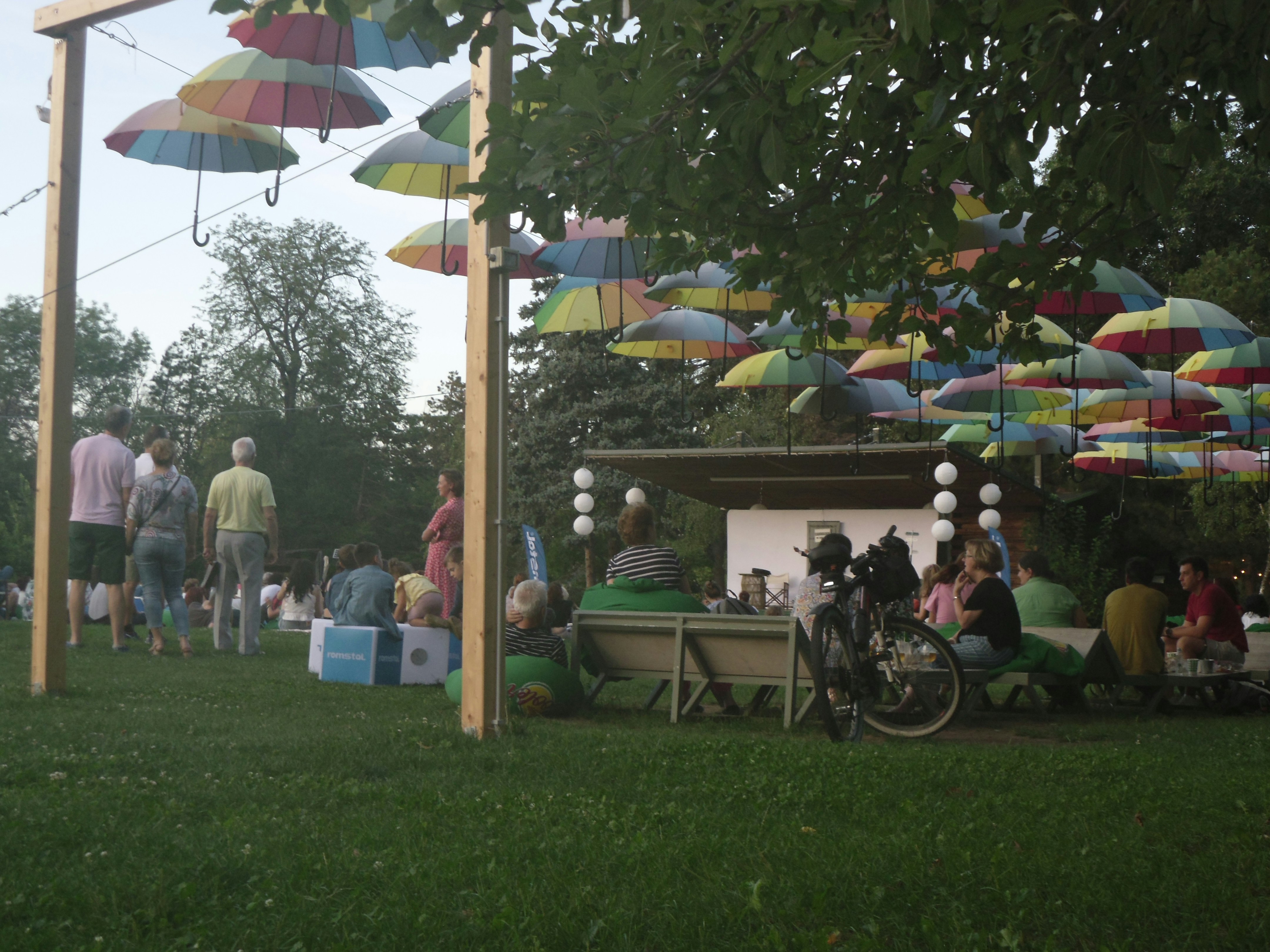A group of people sitting under umbrellas in a park