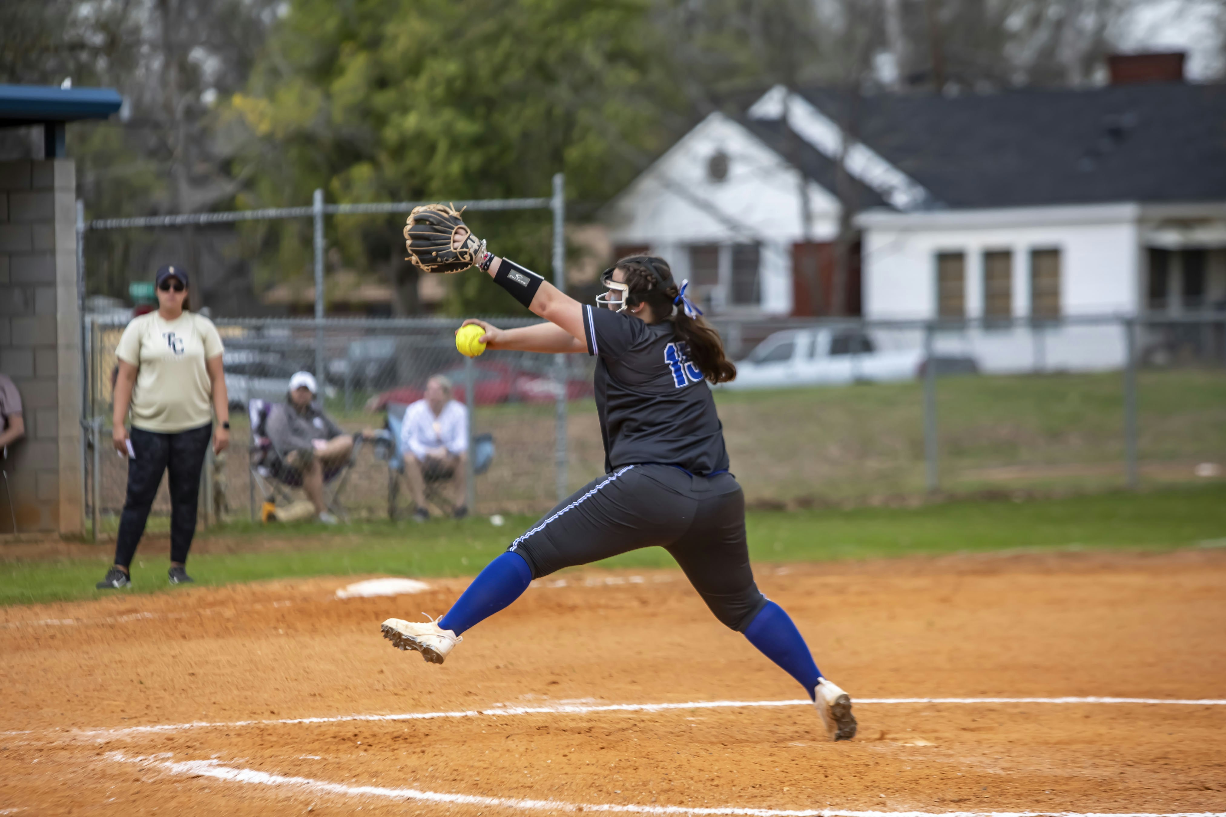 A woman pitching a baseball on top of a field