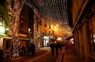People walking down a street covered in christmas lights