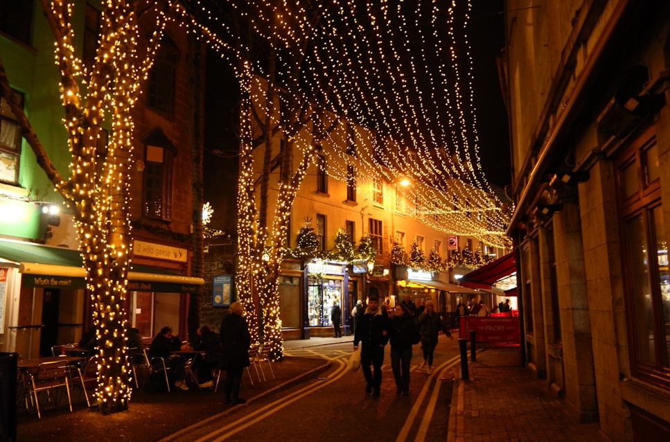 People walking down a street covered in christmas lights