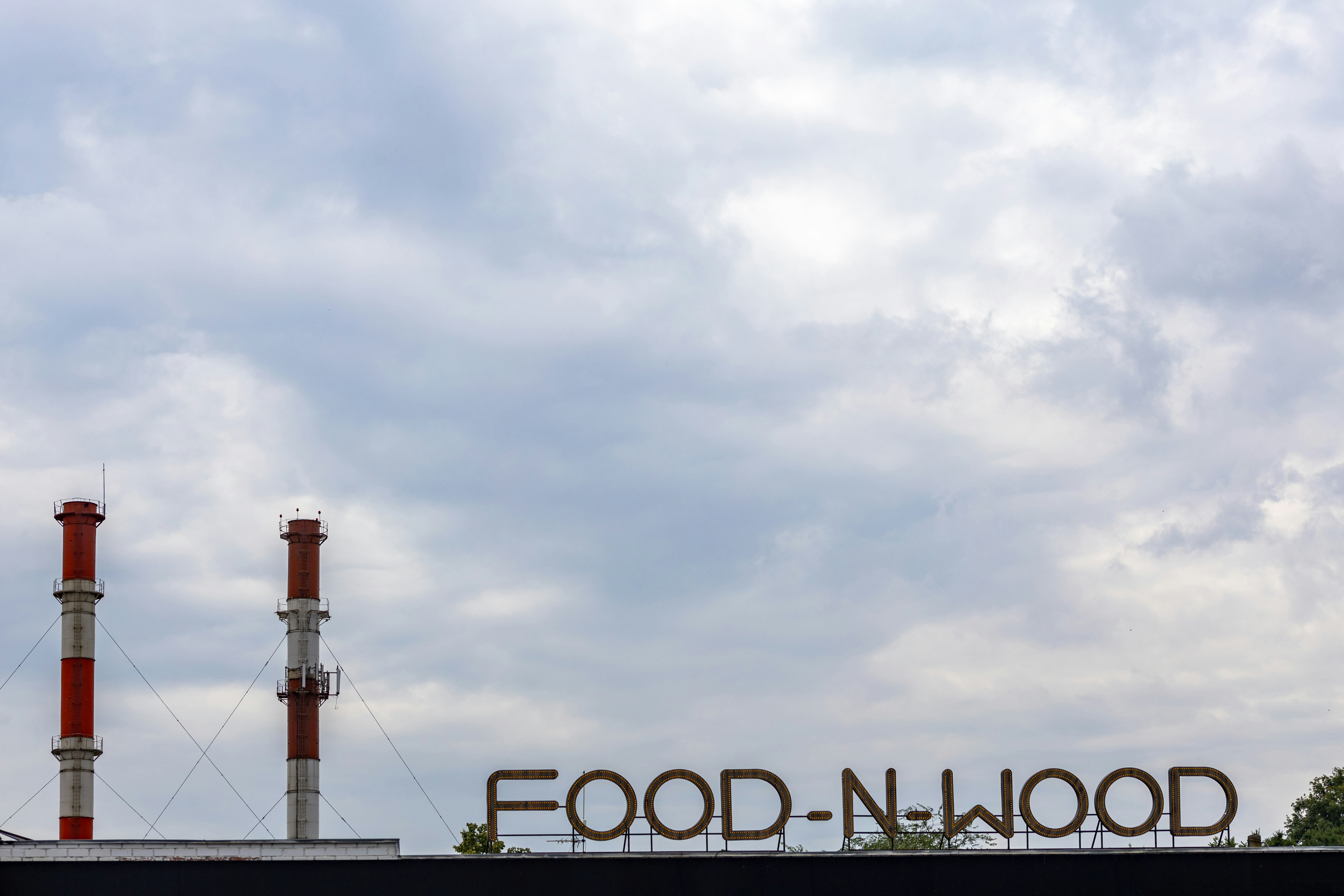A sign for a food - n - wood plant on a cloudy day