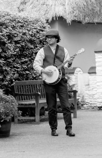 A man standing next to a bench holding a guitar