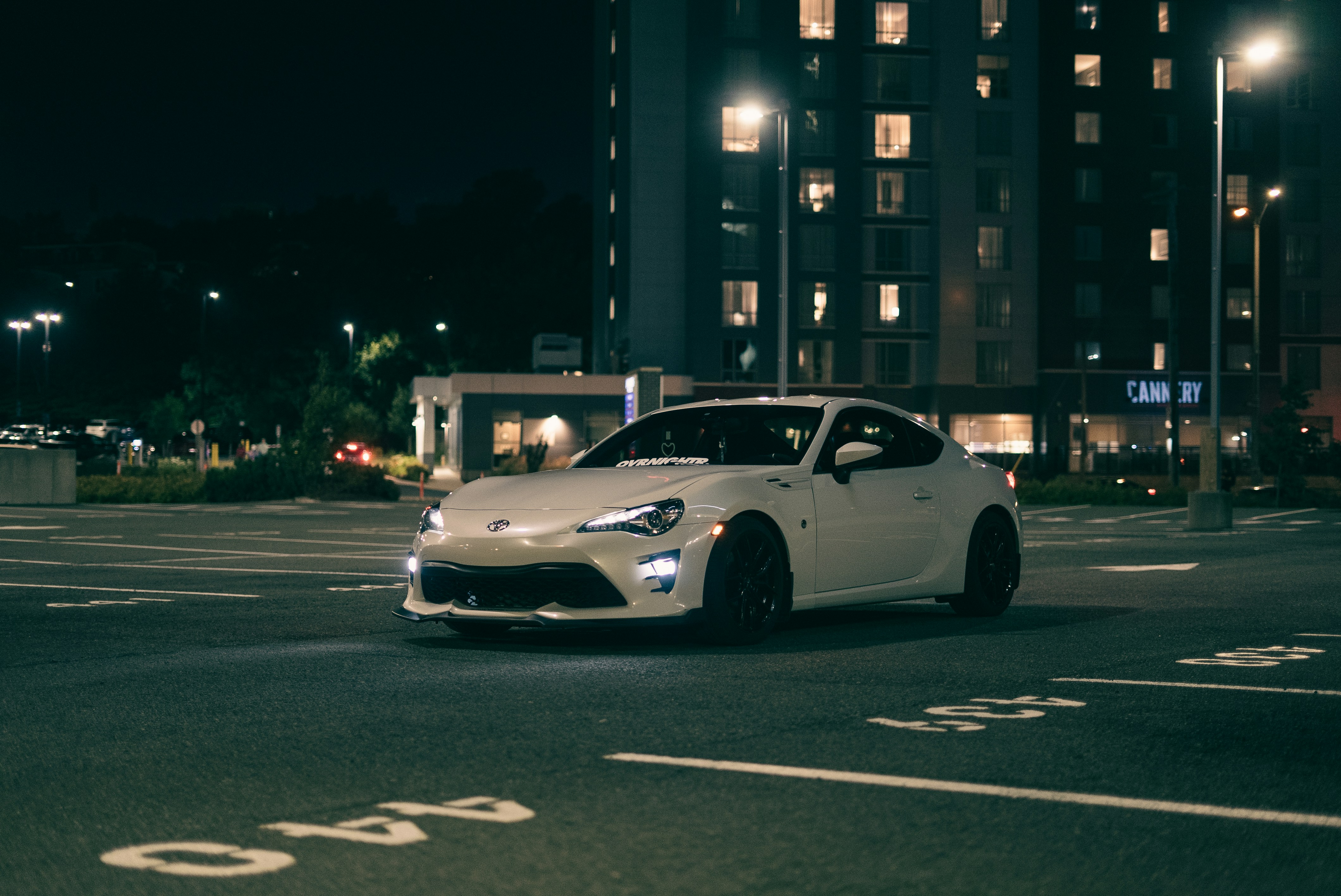 A white car driving down a street at night photo – Free Automobile ...