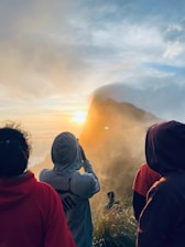A group of people standing on top of a grass covered hillside