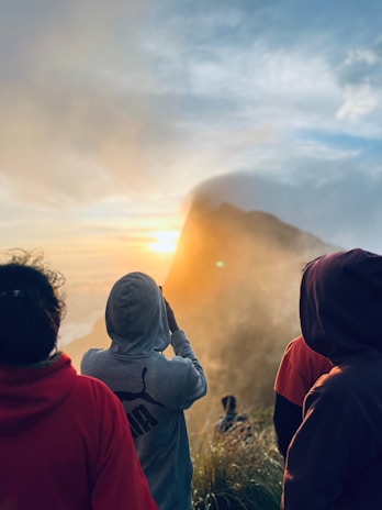 A group of people standing on top of a grass covered hillside